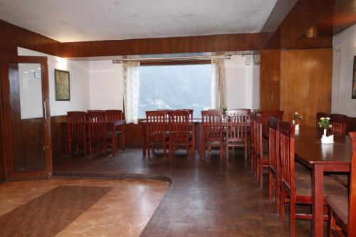 una sala da pranzo con sedie in legno, tavolo e finestra di Hotel De Villa Gangtok a Gangtok