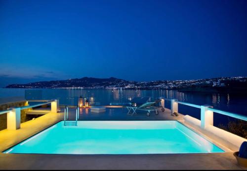 a swimming pool with a view of the water at night at Villa Maestro Mykonos in Agios Ioannis Mykonos