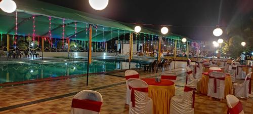 a banquet hall with tables and chairs and a pool at Mango Valley Resort Ganpatipule in Ratnagiri