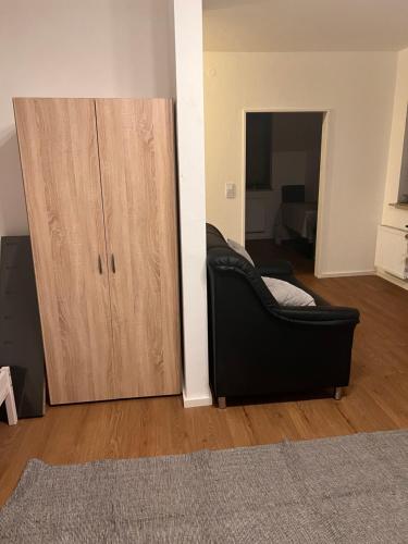 a black couch in a living room next to a cabinet at Monteurunterkunft Heger - Beste Verkehrsanbindung in Aalen