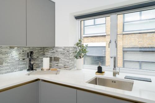 a white kitchen with a sink and a window at Oxford Street 2 Bedr, 3 Beds, 2,5 Bath, 2 min subway in London