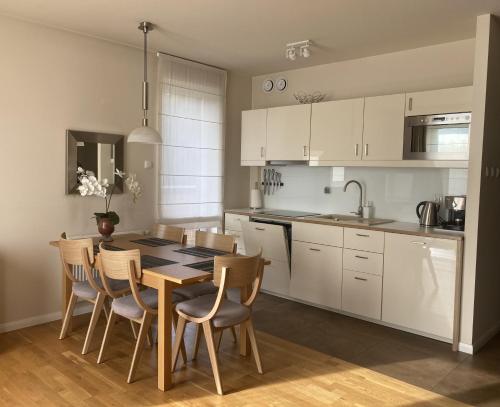 ポラニツァ・ズドルイにあるApartament Beigeの白いキャビネット、テーブルと椅子付きのキッチンが備わります。
