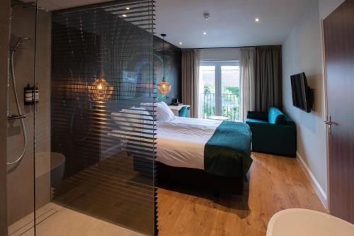 a bedroom with a bed and a glass wall at Hotel Sanders de Paauw in Sluis