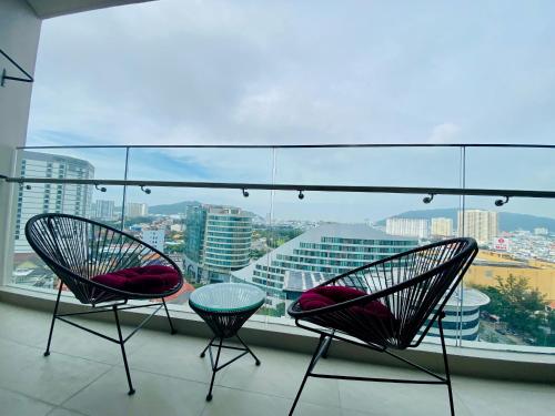 two chairs on a balcony with a view of a city at The Sóng Vũng Tàu - Mochi House in Vung Tau