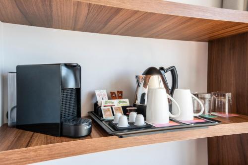 a shelf with a coffee maker and cups on it at Hotel Santiago Plaza Affiliated by Meliá in Santiago de Compostela