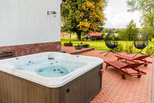 a hot tub on a patio with two chairs at Stara Szkoła Browina in Browina