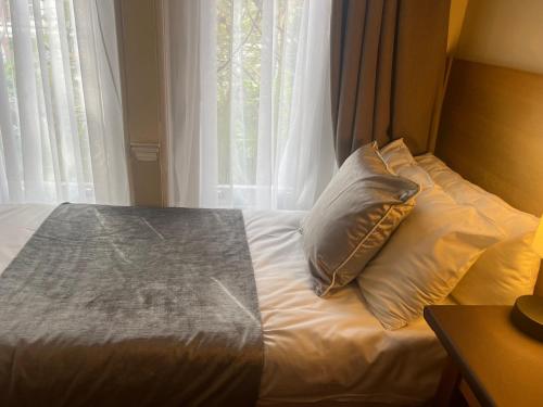 a bed with a pillow in front of a window at Hotel Cavendish in London