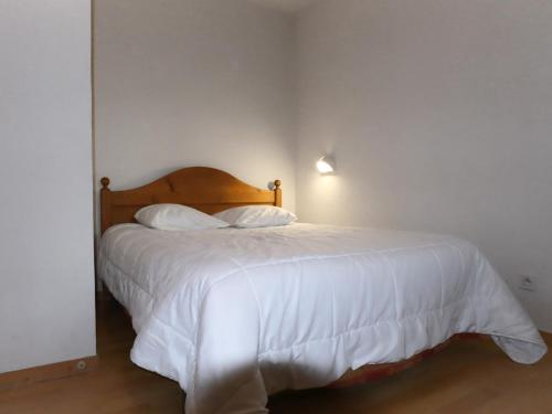 um quarto com uma cama com lençóis brancos e almofadas em Appartement Samoëns, 2 pièces, 5 personnes - FR-1-624-102 em Samoëns