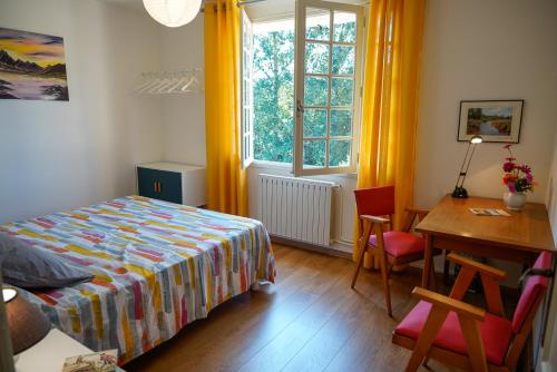 1 dormitorio con cama, escritorio y ventana en Aux Peupliers, en Le Malzieu-Ville