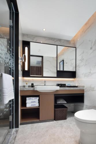 a bathroom with a sink and a mirror at Hampton By Hilton Shenzhen Futian Mangrove Park Apartments in Shenzhen