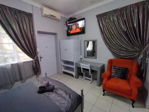 a bedroom with a bed and a tv and a chair at 21on2nd Avenue in Tzaneen