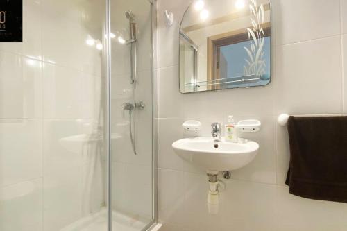 Un baño con lavabo y ducha de cristal. en Beautiful, TOP NOTCH 1 BR APT just off the coast by 360 Estates, en St Paul's Bay