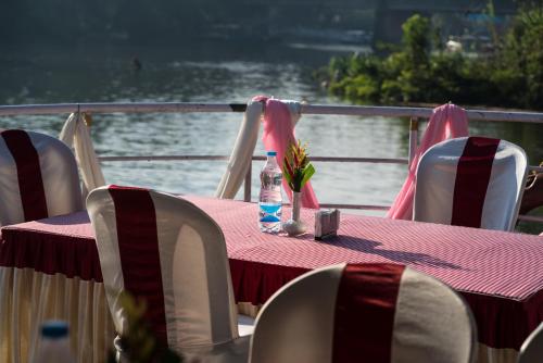 a table with chairs and a bottle of water on a boat at Leela Backwater Inn in Trivandrum