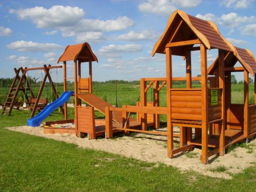 a row of wooden playground equipment in a field at POLE NAMIOTOWE nad rzeką BIEBRZA w GONIĄDZU in Goniadz