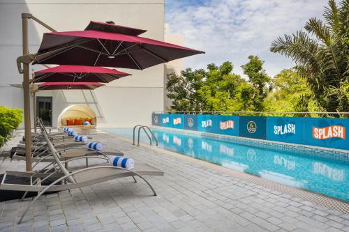a row of chairs with umbrellas next to a swimming pool at Travelodge Harbourfront Singapore in Singapore