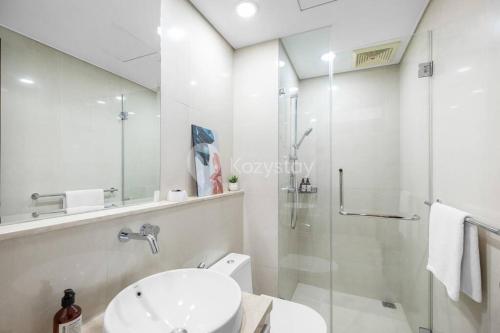a white bathroom with a sink and a shower at MOIRA by Kozystay 2BR Great Location & Bathtub in Jakarta