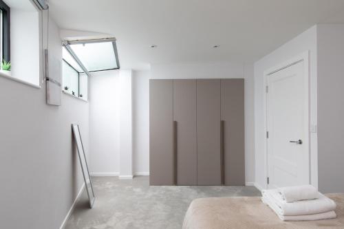 um quarto branco com uma cama e uma janela em homely - Central London Camden Town Apartments em Londres