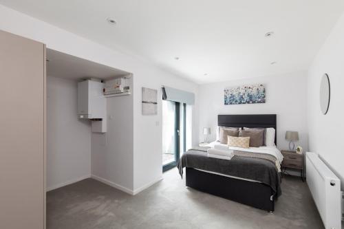 homely - Central London Camden Town Apartments في لندن: غرفة نوم بيضاء بها سرير ونافذة