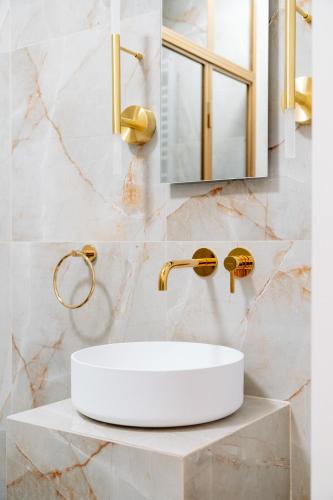 a bathroom with a white sink and gold faucet at Warsaw Story - LoftAffair Collection in Warsaw