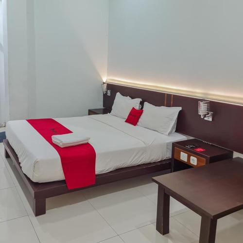 een slaapkamer met een groot bed en een rode deken bij RedDoorz Plus at Hotel Royal Palangka Raya in Palangkaraya