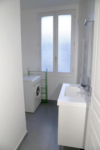 La salle de bains blanche est pourvue d'un lavabo et d'un lave-linge. dans l'établissement Appartement 3 pièces, à Honfleur