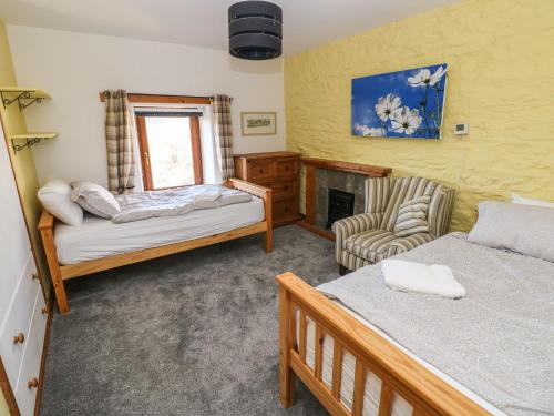a bedroom with two beds and a chair and a fireplace at Nant Moel Isaf Farm in Swansea