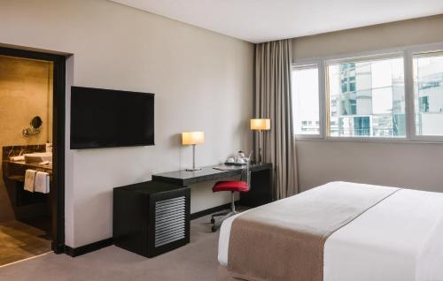 a hotel room with a bed and a desk and a television at Mövenpick Hotel Casablanca in Casablanca