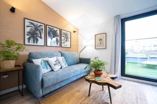 a living room with a blue couch and a table at Palomar de Corrida Atico con terraza in Gijón
