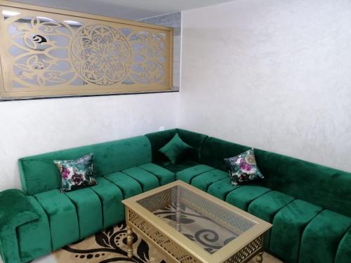 a green couch in a living room with a table at Appartement lux dakhla in Dakhla