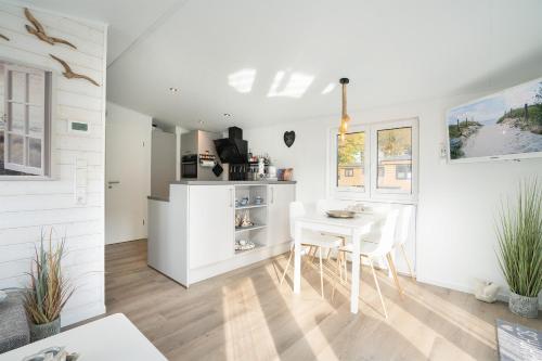 a kitchen and dining room with a white table and chairs at Ostseecamp Lübecker Bucht Haus Ankerplatz in Scharbeutz