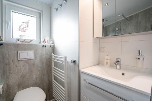 a white bathroom with a toilet and a sink at Ostseecamp Lübecker Bucht Haus Ankerplatz in Scharbeutz