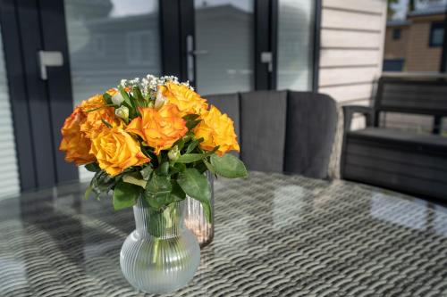 a vase filled with orange flowers on a table at Ostseecamp Lübecker Bucht Haus Ankerplatz in Scharbeutz
