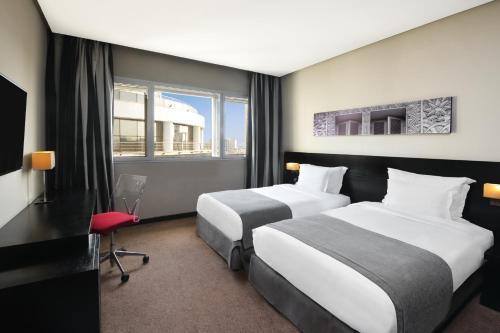 a hotel room with two beds and a desk at Mövenpick Hotel Casablanca in Casablanca