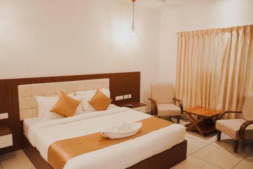 a bedroom with a bed and a table and chairs at Sprise Munnar Resort and Spa in Munnar