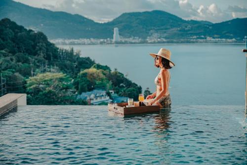 una mujer sentada en el agua en el agua en Wyndham Grand Phuket Kalim Bay, en Patong Beach