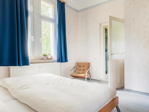a bedroom with blue curtains and a bed and a chair at Ferienwohnung Rorik - Schierke in Schierke