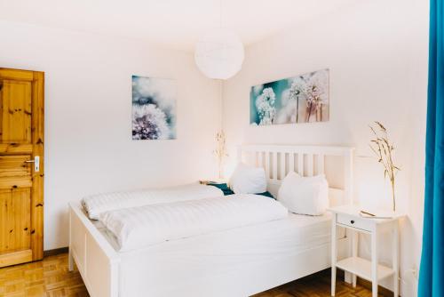 ブラウンラーゲにあるHarz Zeit Braunlageの白いベッドと壁に2枚の絵が飾られた白いベッドルーム1室が備わります。