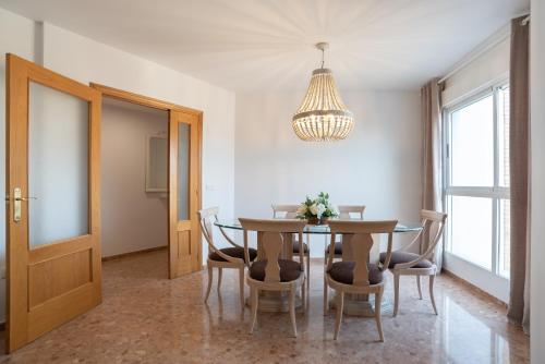una sala da pranzo con tavolo, sedie e lampadario pendente di Magnifico apartamento en Burriana a Burriana
