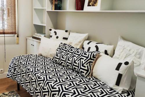 uma cama com almofadas pretas e brancas num quarto em Ultreia , piso turístico termal em Ourense