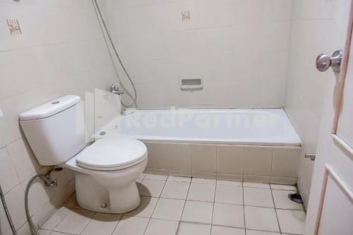 a bathroom with a toilet and a bath tub at Graha Sartika Hotel RedPartner in Bandung