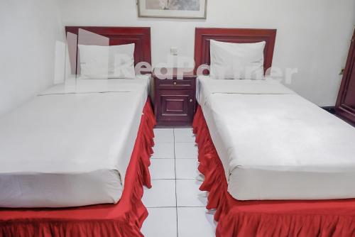 two beds sitting next to each other in a room at Graha Sartika Hotel RedPartner in Bandung