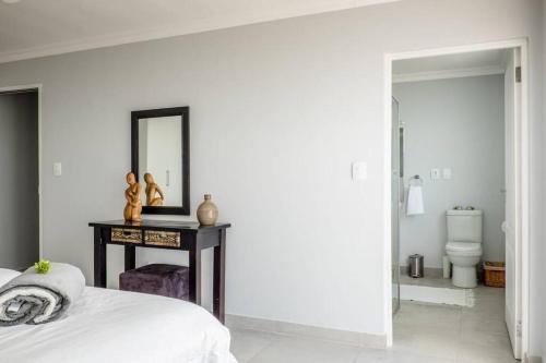 a bedroom with a bed and a mirror on a table at Driftwood Beachfront Manor - Shelley Point in St Helena Bay