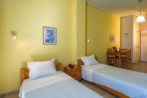a room with two beds and a dining room with a table at Hotel Fotini in Kalamata