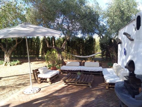 un patio con sofás blancos y una sombrilla en La Casa del Abuelo Jose en Marmolejo