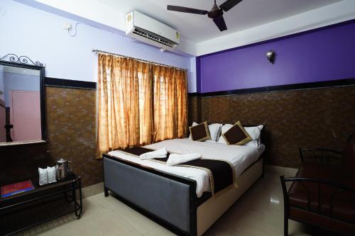 a bedroom with a large bed with a purple wall at Tirupati Lodge NJP in Siliguri