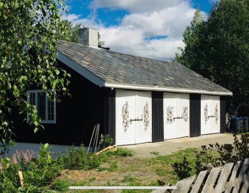 a black and white shed with white doors at Traditional timber farm with Sauna & Wi-Fi in Baukål