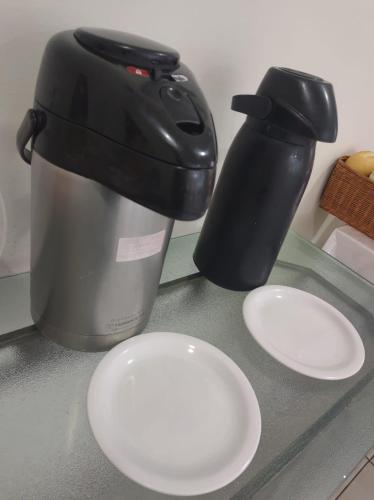 a coffee maker and two white plates on a counter at RUBY HOSPEDAGENS in Indaiatuba