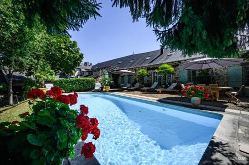 a swimming pool with red flowers next to a house at Maison d'hôtes Les jardins Saint Eloi in Le Lonzac