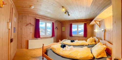 2 Betten in einem Zimmer mit Holzwänden in der Unterkunft Heuberge in Fideris Dorf