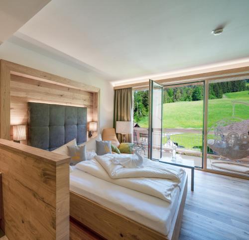 a bedroom with a large bed and a large window at Ruhehotel & Naturresort Rehbach - Adults only in Schattwald